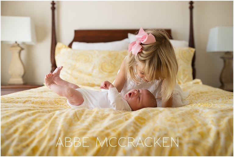 Newborn lifestyle photography session - candid moment of big sister and baby brother on bed