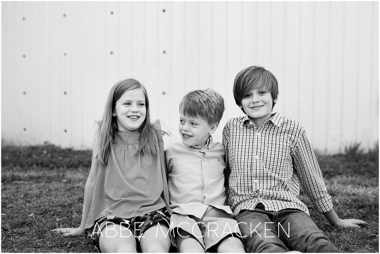 Candid black and white picture of three siblings taken during a family photography session