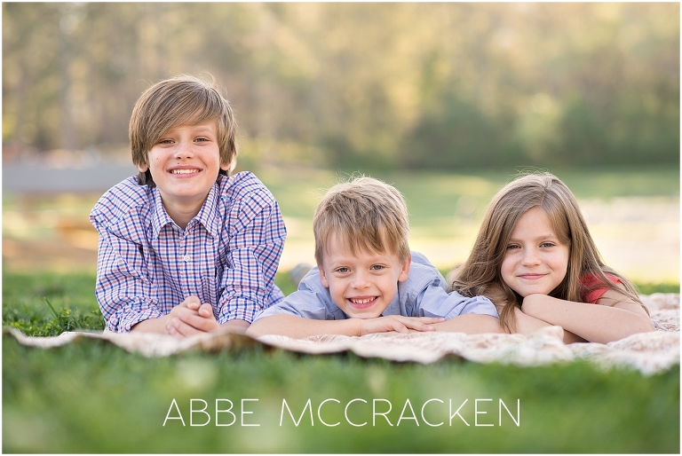 Image of three siblings laying on a blanket in Charlotte, North Carolina's Freedom Park