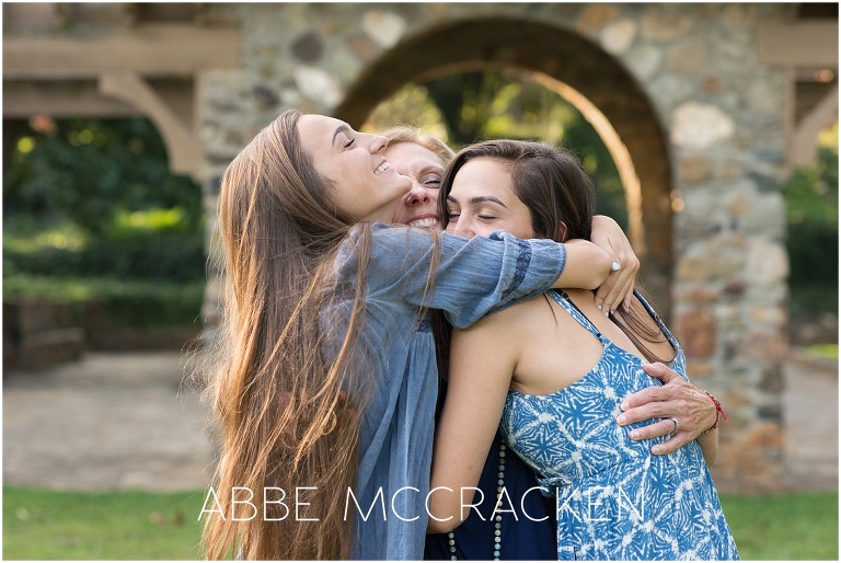 Joyful photo of teenage daughters including one high school senior embracing their mom