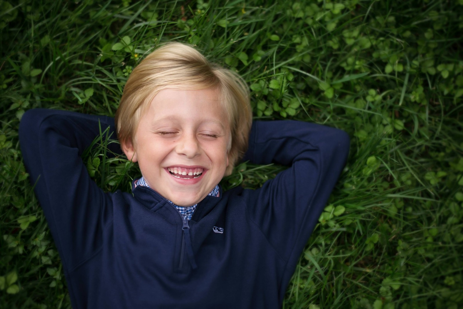 young boy laying in the grass and laughing
