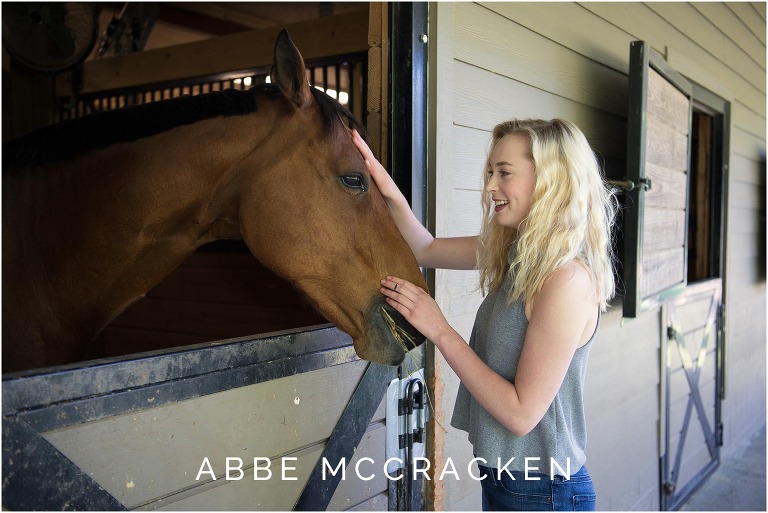 High school senior petting her horse at the barn in Waxhaw, NC