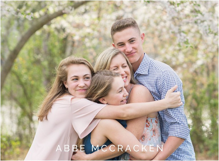 Candid image three teenage children hugging their mother - spring family session