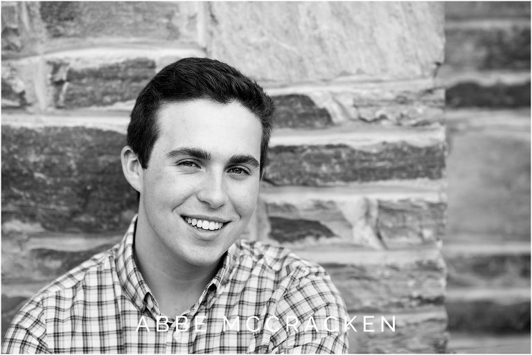 Close up headshot of high school senior guy against stone wall