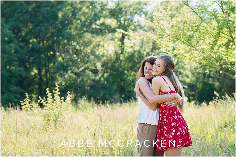 Color image of a mother and her high school senior daughter hugging in the tall grasses of Marvin Efird Park, Marvin NC