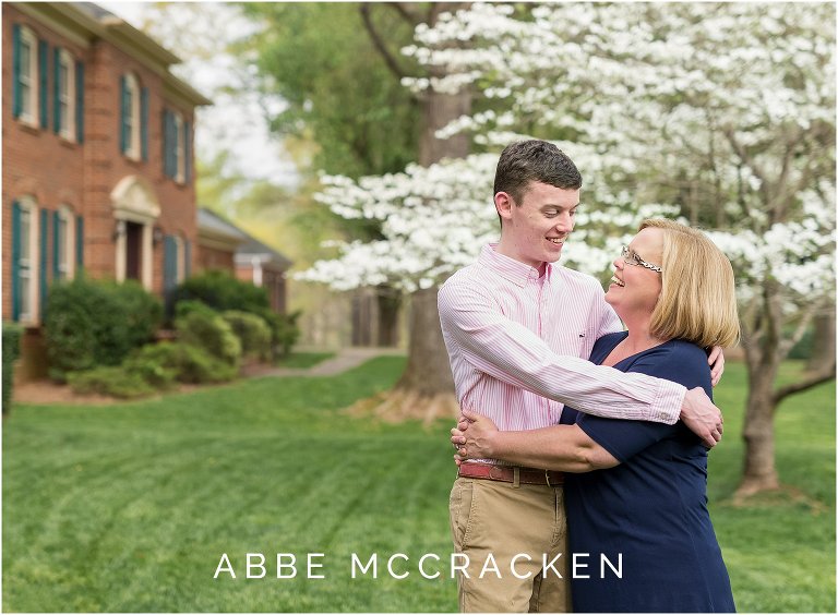 Photograph of mother and her son, a high school senior, standing in their yard with a gorgeous blooming dogwood tree behind them.