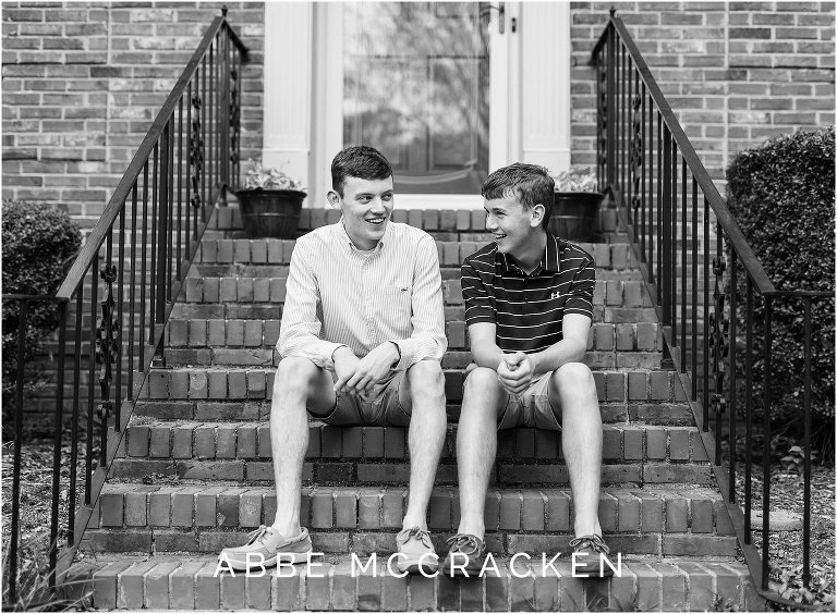 Candid senior portrait with a sibling - two boys laughing at each other on the front porch steps of their home