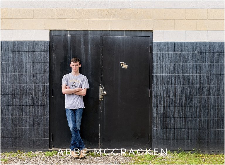 Senior boy leaning on athletic doors at Providence High School in Charlotte NC