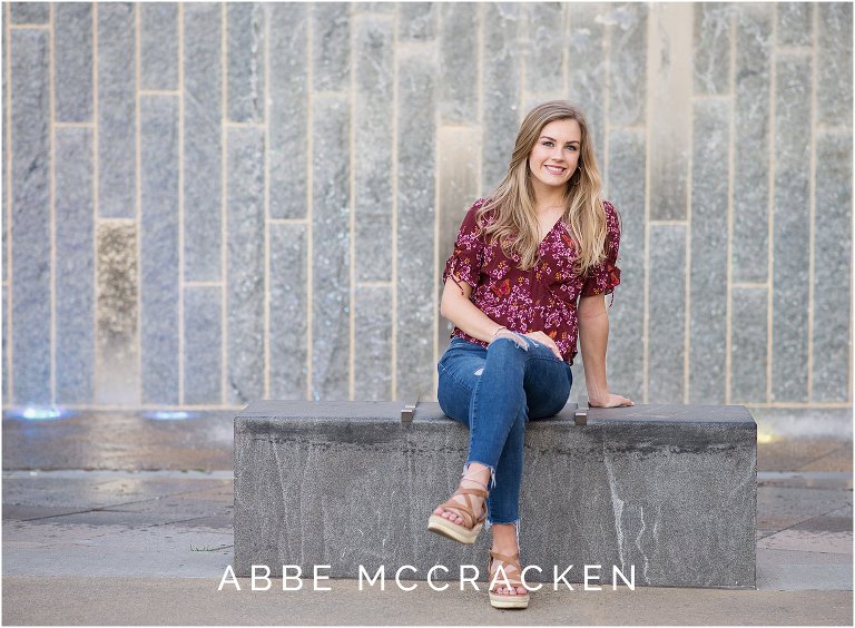 Stunning blonde high school senior in front of the waterfall at Romare Bearden Park in Charlotte, NC