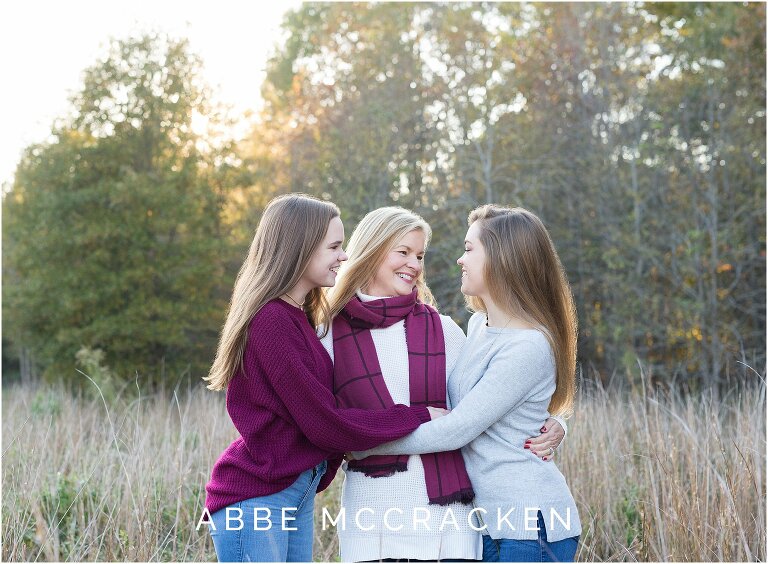 Mother hugging her two teenage daughters, one is a high school senior