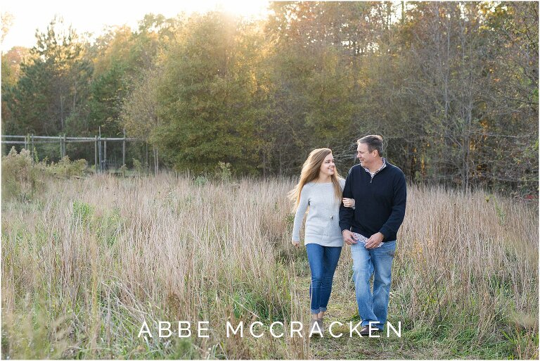 High school senior walking arm and arm with her father, laughing at each other