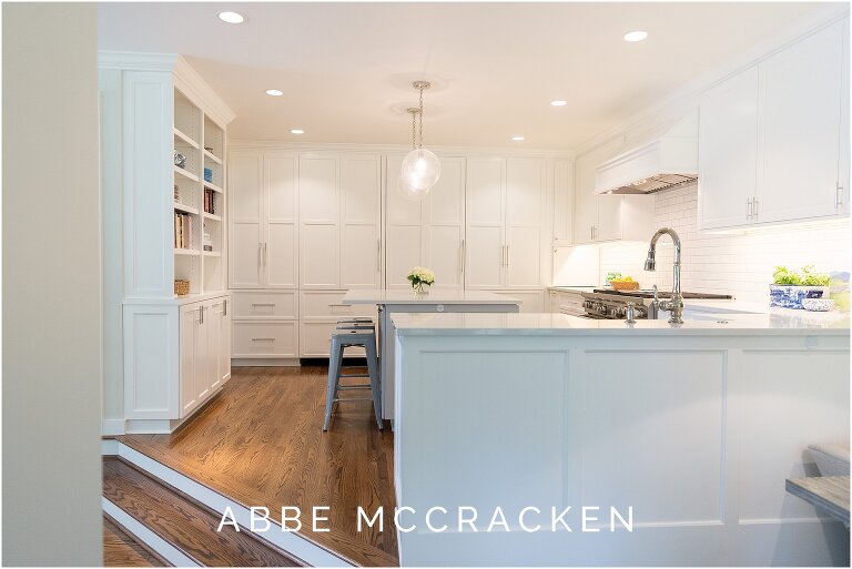 Overview of kitchen and wall of cabinets, one opens to reveal a laundry room