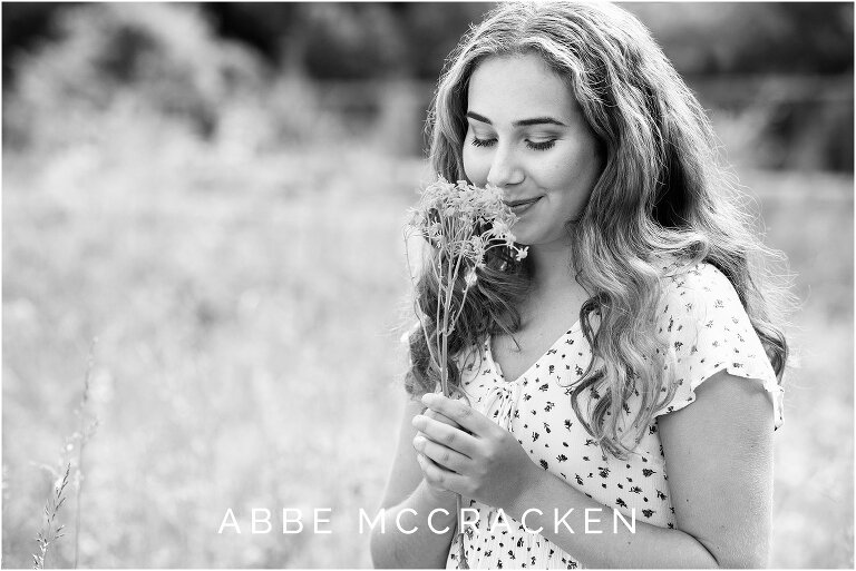 black and white candid portrait of a girl holding a flower