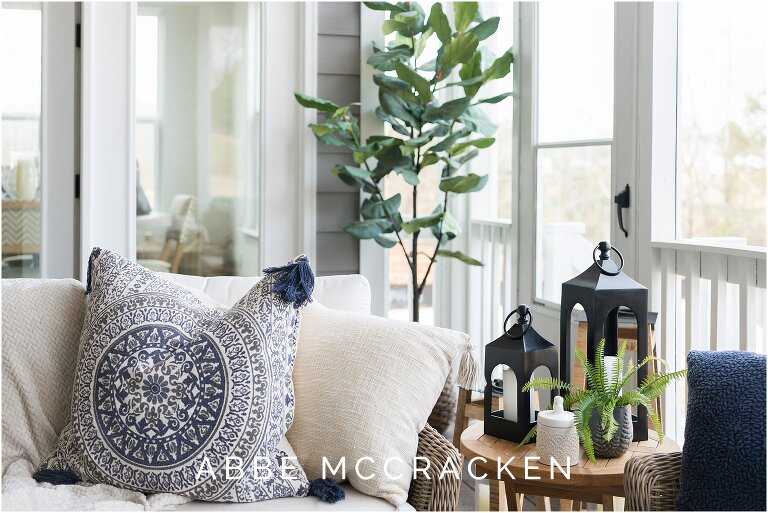 screened in porch decorated with pillows, candles, greenery