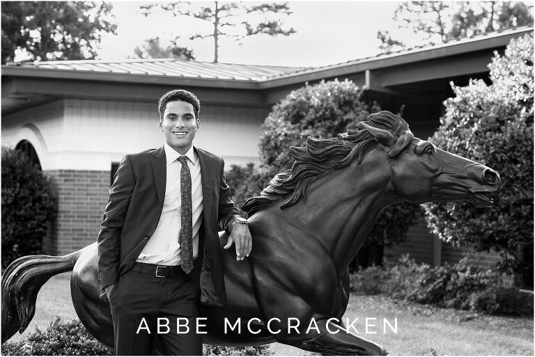 Providence Day Senior leaning on Charger statue