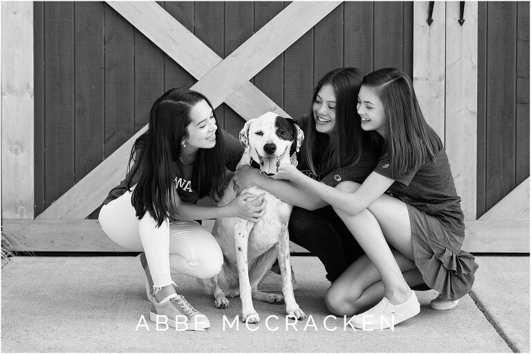 Black and white of sibling girls, teenagers with their dog