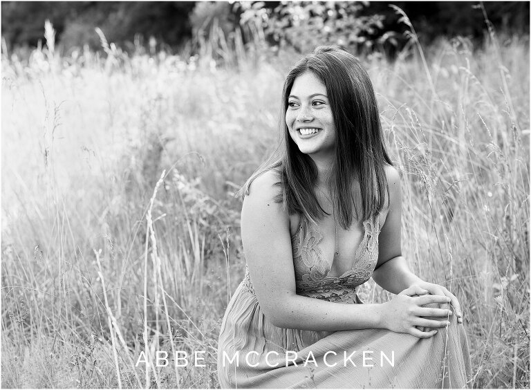 Candid black and white senior picture of recent high school graduate in long flowy dress