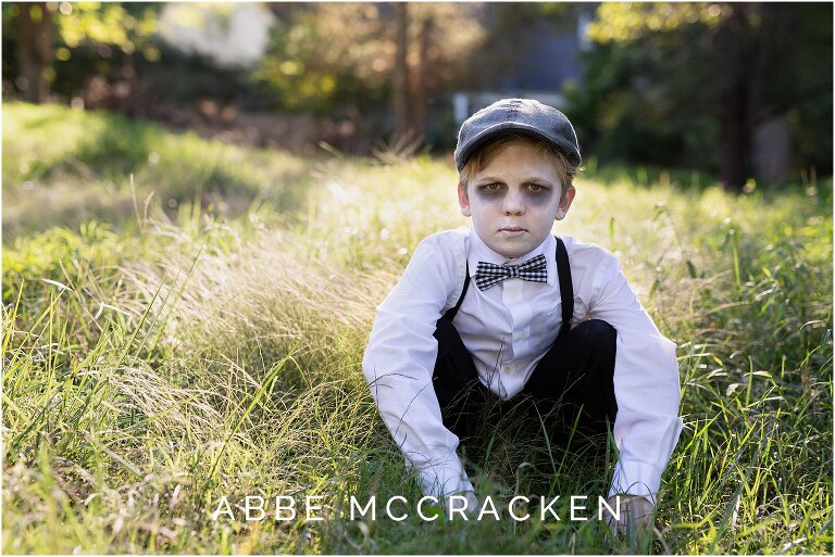 young boy dressed as a ghost crouched in the grass