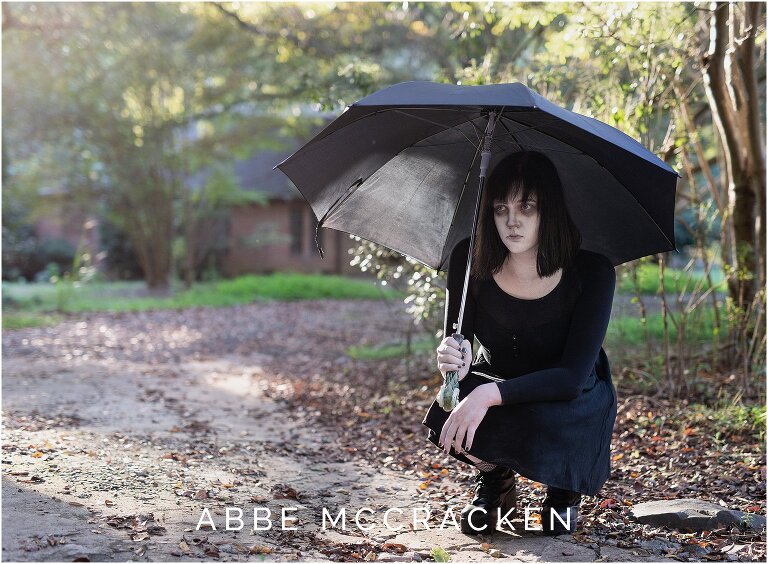 Teenage ghost girl hiding under an umbrella to avoid the light