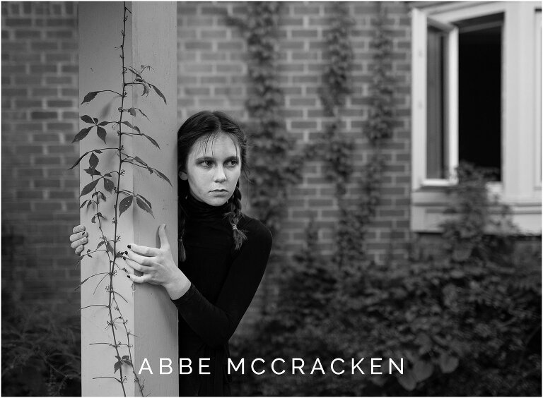 Creepy image of young ghost girl peeking around a pole with overgrown vines