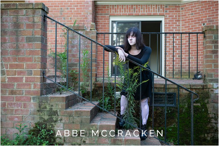 Teen daughter dressed as a ghost standing on steps of abandoned rundown home
