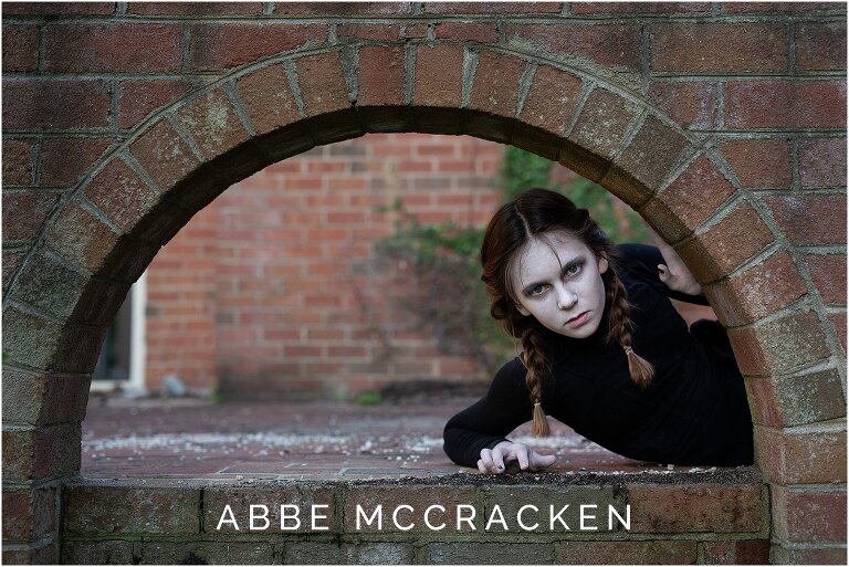 Halloween picture of a ghost girl peeking thru a brick archway of abandoned home
