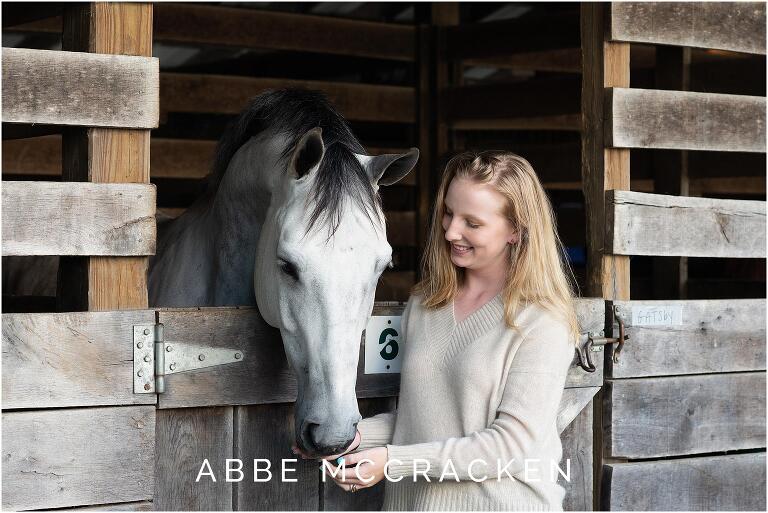 Senior girl and her white horse photographed in stables at Blowing Rock Equestrian Preserve