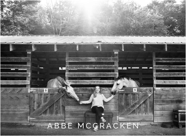 Senior portraits with horses at Blowing Rock Equestrian Preserve, black and white image with sun flare above the horse stables