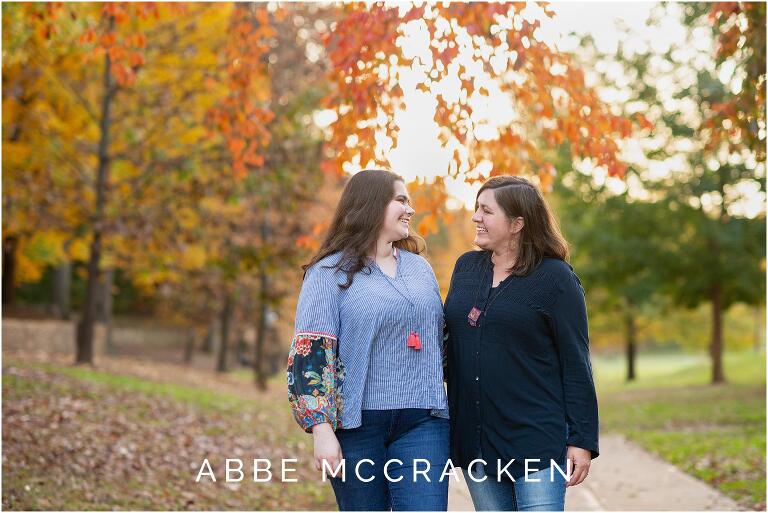 Candid senior portrait of a mother and her daughter laughing at each other, set against the beautiful fall colors in Charlotte's Independence Park