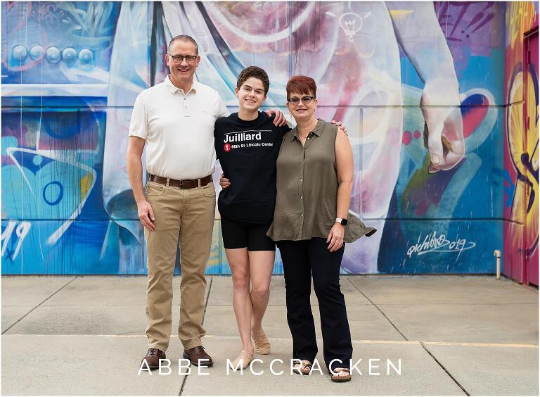 High school senior dancer and his parents in front of Charlotte Ballet mural