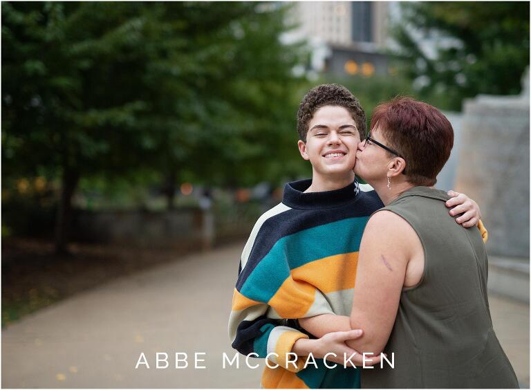 Candid senior portrait of mom kissing her son on the cheek