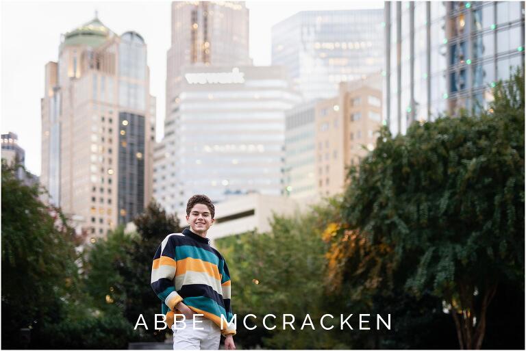 Senior picture of a boy in colorful sweater and white jeans in Romare Bearden Park