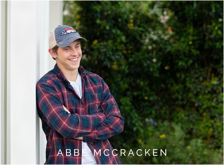 Candid senior portrait of a boy wearing a North Carolina hat, flannel shirt