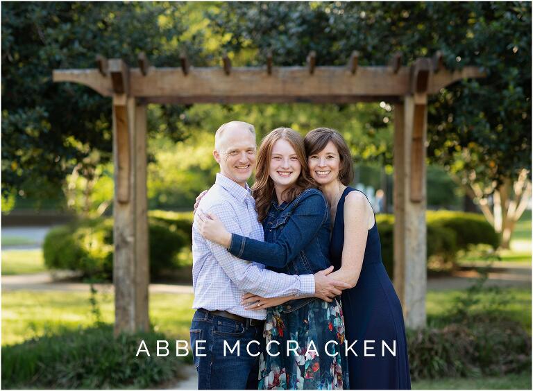 Mother and father hugging high school senior daughter
