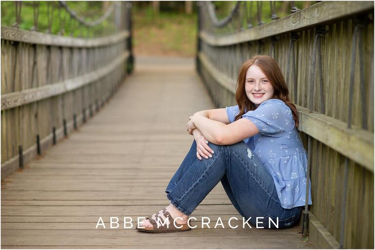 Senior picture of gorgeous red head in jeans, berkinstocks and blue shirt