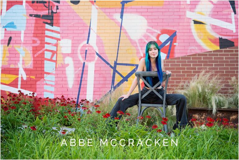 Senior portrait of a dancer in black posing in front of a colorful Camp North End mural