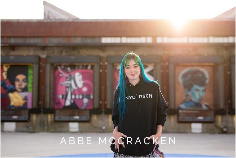 Senior dancer wearing NYU Tisch sweatshirt, illuminated by sun flare, photographed at Charlotte's Camp North End