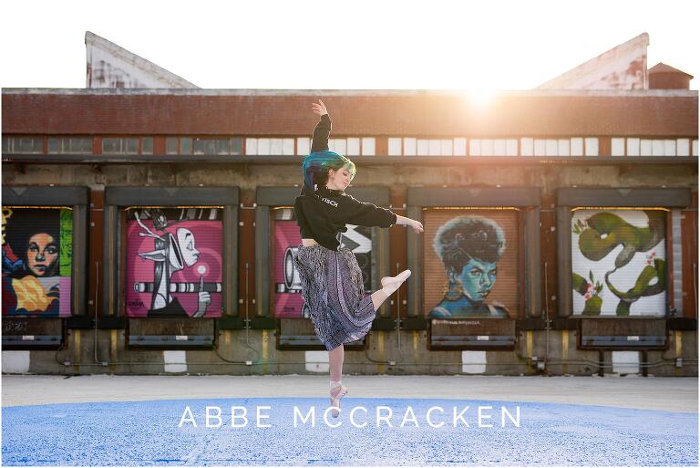 Senior portrait of a ballet dancer jumping in front of murals at Camp North End, Charlotte