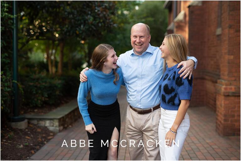 Candid image of father and two teenage daughters laughing