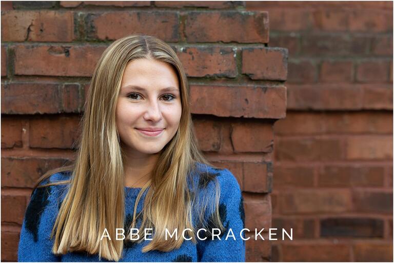 Senior portrait in blue on a red brick wall