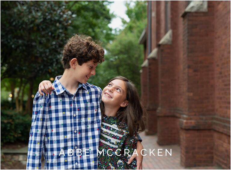 Candid image of a bother and sister hugging and smiling at each other