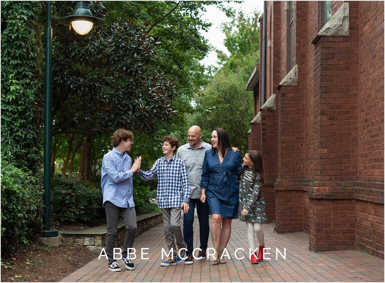 Family walking together and giving oldest brother - a high school senior - a high five