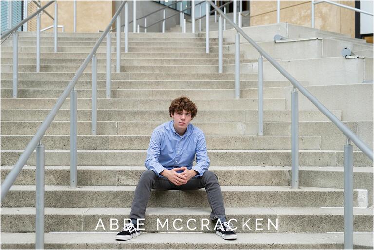 portrait of a high school senior boy sitting on the steps of the Mint Museum in Uptown Charlotte