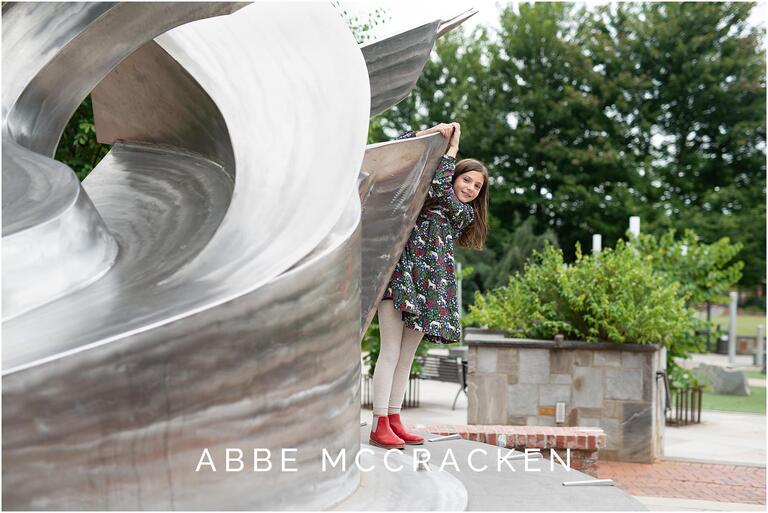 Young girl playing in statue on Romare Bearden Park