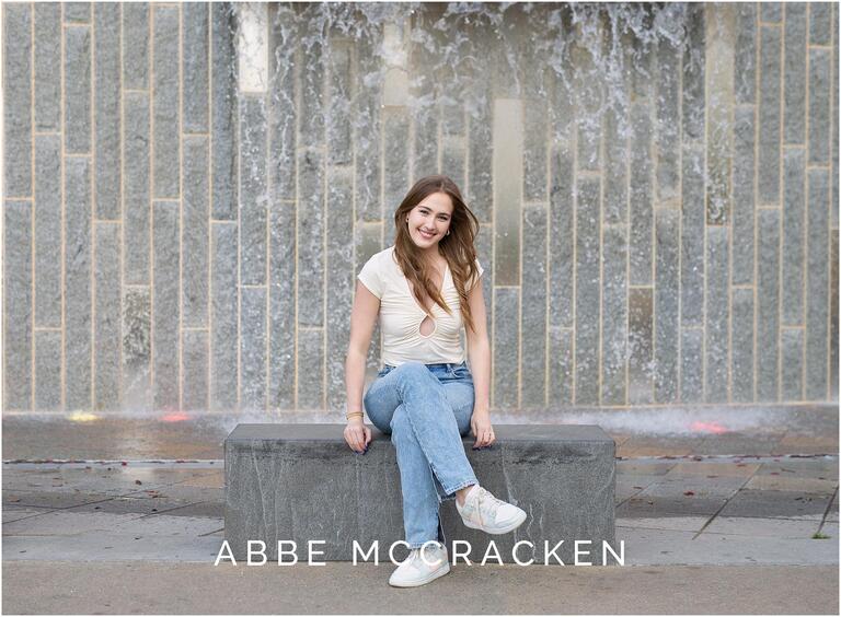 Casual photo of a girl in jeans, sitting on stonework in Romare Bearden Park, Charlotte