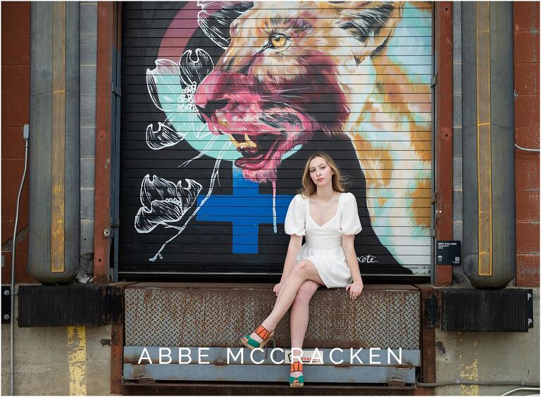 Senior picture sitting on a loading dock with painted mural