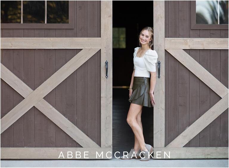 Senior portrait of a girl leaning on the barn doors at Marvin Efird Park in Waxhaw, North Carolina