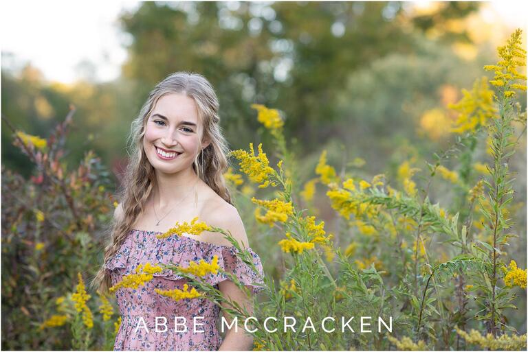 Senior portrait of a girl with blond loose curls and floral pink dress