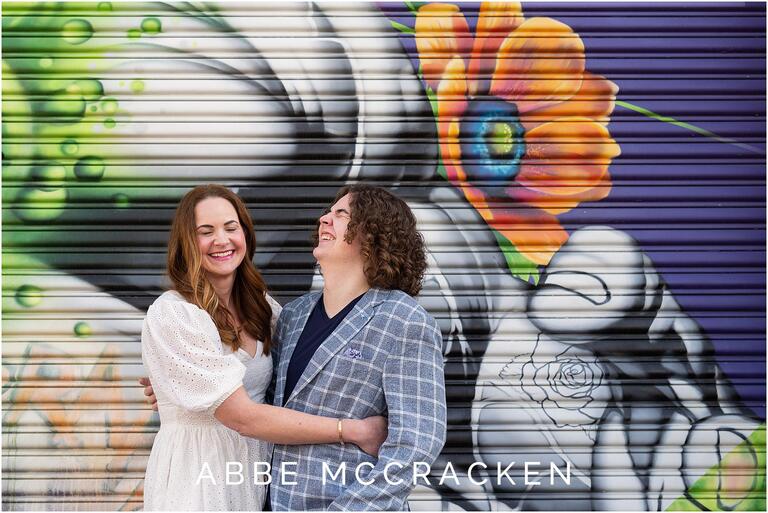 Mother and son laughing, standing in front of a colorful mural at Camp North End