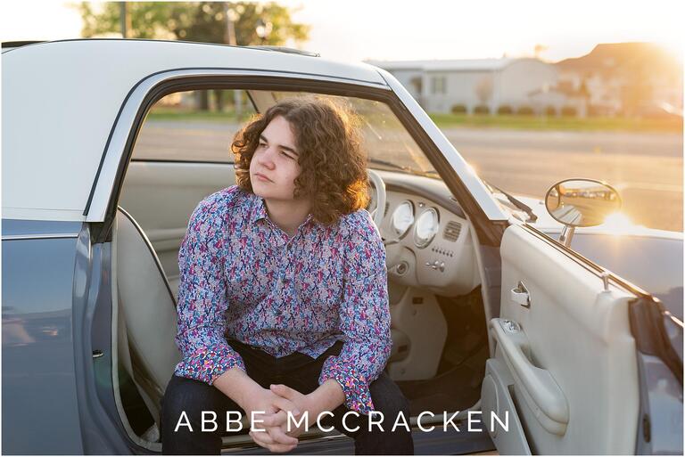 Senior portrait sitting in Charlotte the Figgy, a 1991 Nissan Figaro
